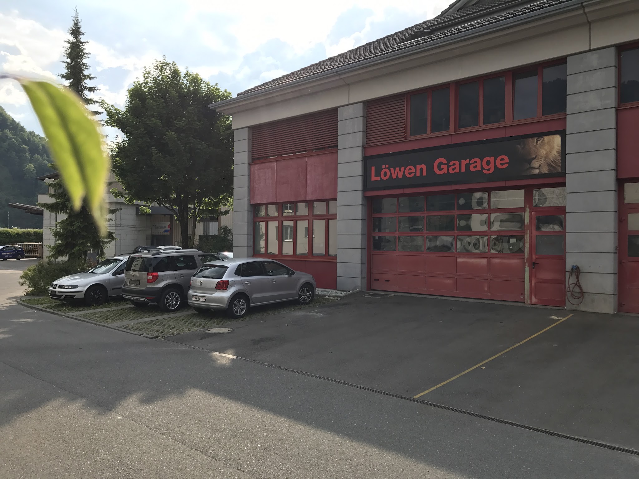 Werkstattgebäude der Löwen Garage mit rotem Rolltor und Schriftzug an der Fronhofenstrasse in Stans
