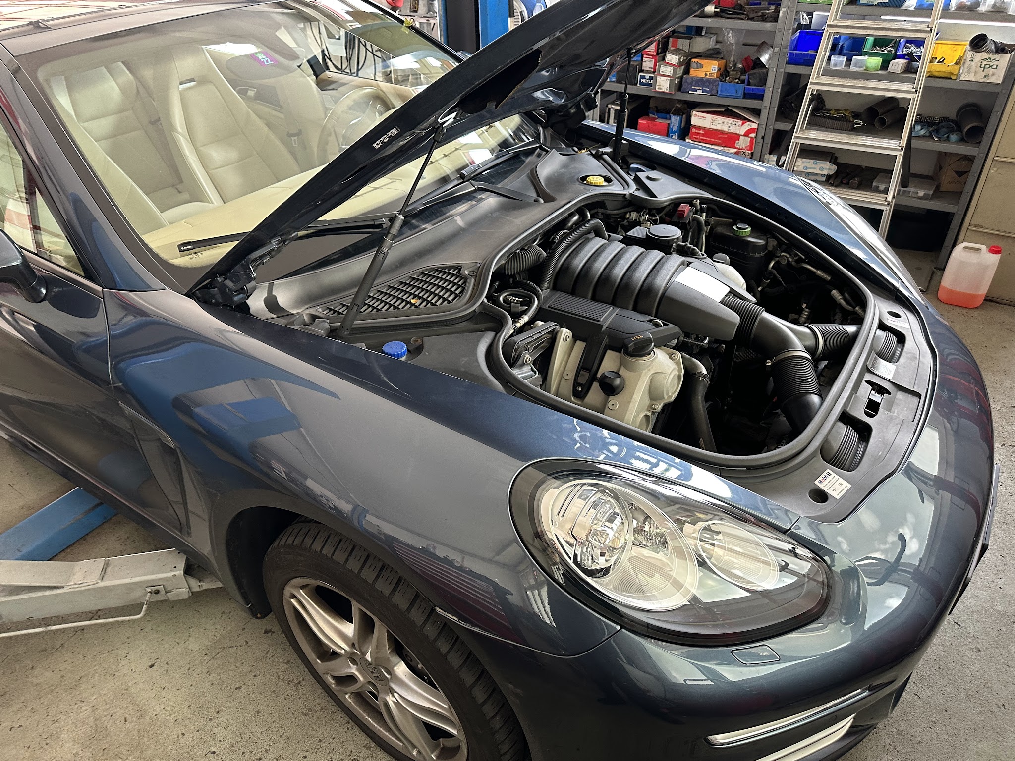 Porsche Cayenne mit geöffneter Motorhaube in der Werkstatt